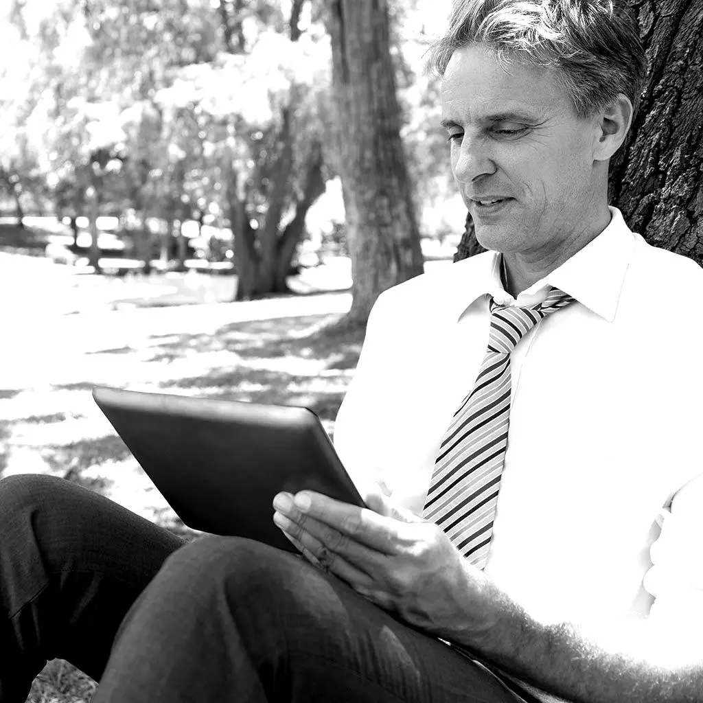 Mann lernt eine Sprache unter einem Baum mit einer Tafel